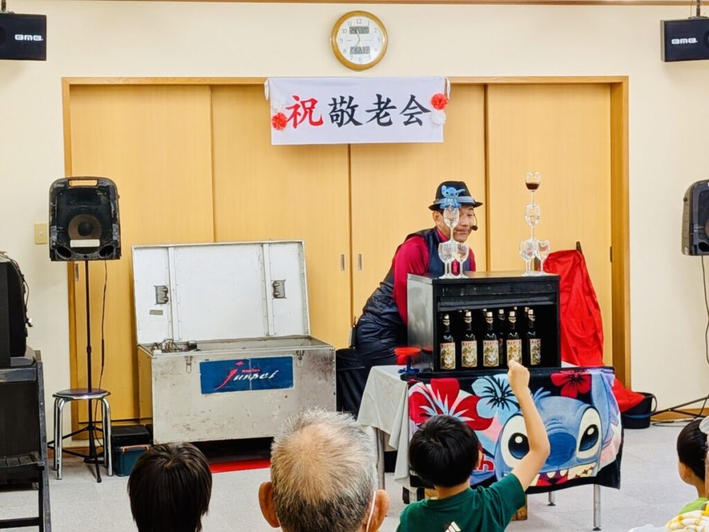 マジシャンJUNPEIが三重県鳥羽市の敬老会イベントでマジックショーを披露している様子。とっても盛り上がっている中グランドフィナーレでテーブルクロス引きに成功した瞬間